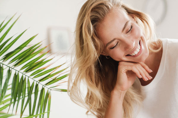 Une femme qui sourit avec la tête sur la main