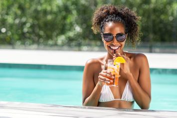 Une femme dans une piscine avec un verre à la main.