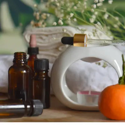 Flacons d’huiles essentielles et diffuseur d’aromathérapie posés dans une ambiance naturelle et végétale.