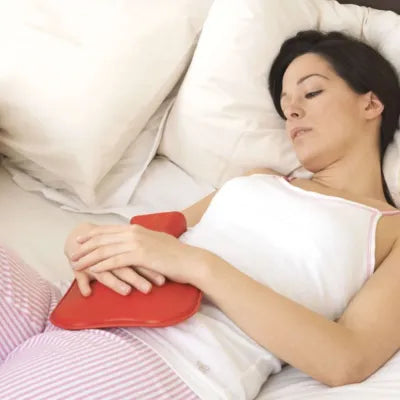Femme qui pose une bouillotte sur son ventre