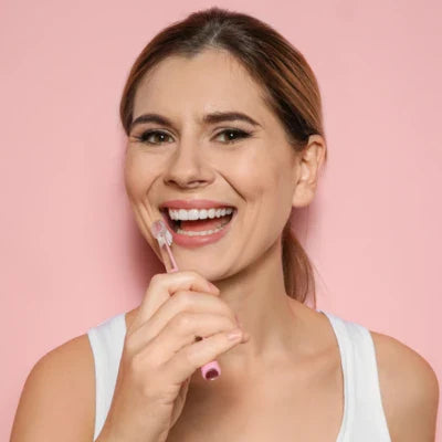 Femme se brossant les dents avec une brosse à dents rose, pour illustrer l’hygiène buccale et les soins dentaires.