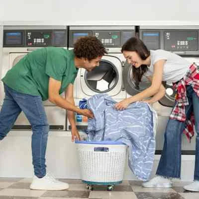 Un homme et une femme qui mettent le linge dans la machine à laver