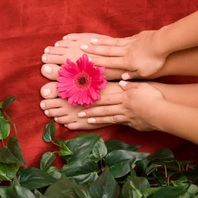 Mains posées sur des pieds avec une fleur rose, pour illustrer les soins naturels des mains et des pieds.