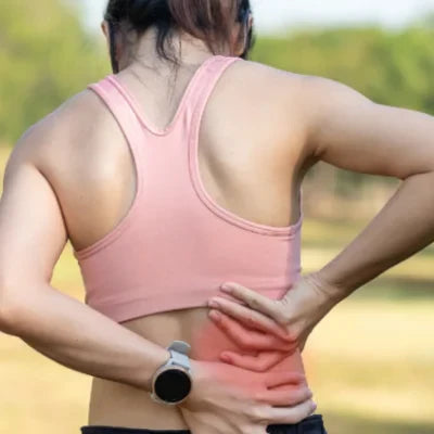 Femme qui a mal en bas du dos à cause de tensions articulaires et musculaires