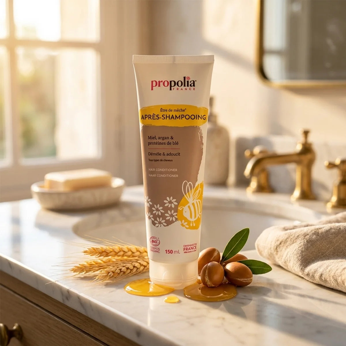 Après-shampoing bio Propolia miel argan blé sur vanité marbre avec ingrédients naturels