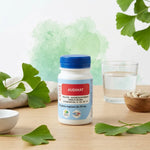 Audinat en gélules avec feuilles de ginkgo biloba et verre d'eau sur bureau wellness