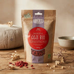 Baies de Goji bio 250g sur table en bois avec fleurs séchées et coussin méditation