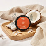 Baume à lèvres coco Najel bio avec noix de coco fraîche et feuilles botaniques sur fond blanc