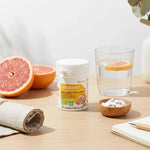 CitroBiotic comprimés bio vegan avec pamplemousse frais et verre d'eau sur plan de travail wellness