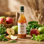 Bouteille de Condiment Pom'Pom bio entourée de pommes fraîches et légumes verts sur table rustique