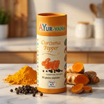 Bouteille Ayurvana Curcuma Poivre noir avec racine fraîche, poivre et poudre dorée sur marbre blanc
