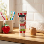 Dentifrice Enfant Fraise Bio Coslys avec accessoires dentaires colorés sur plan de travail salle de bain