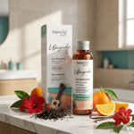 Eau Bronzante l'Originale Aquatéal sur vanité luxe avec feuilles de thé et fleurs rouges