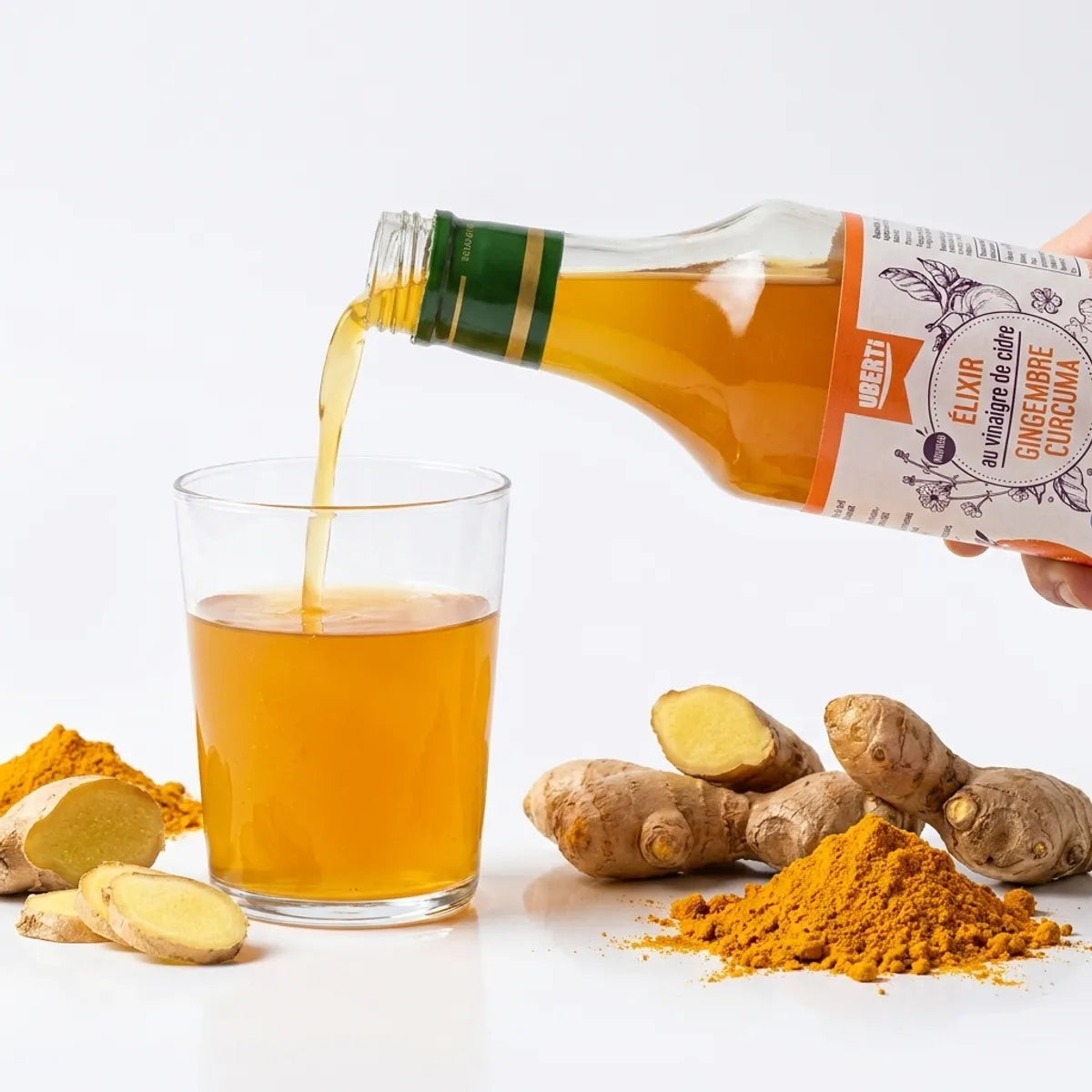 Elixir gingembre-curcuma bio versé dans un verre avec racines et poudre de curcuma frais