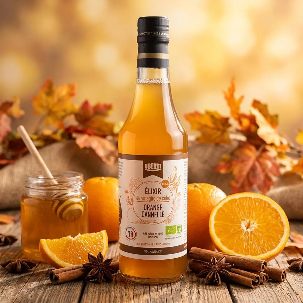 Élixir Orange-Cannelle bio Uberti avec oranges frais et bâtons de cannelle sur bois