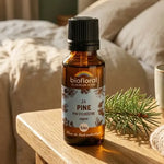 Flacon compte-gouttes ambré de Fleur de Bach Pine bio (pin sylvestre) avec étiquette bleue, posé sur une table de chevet ensoleillée