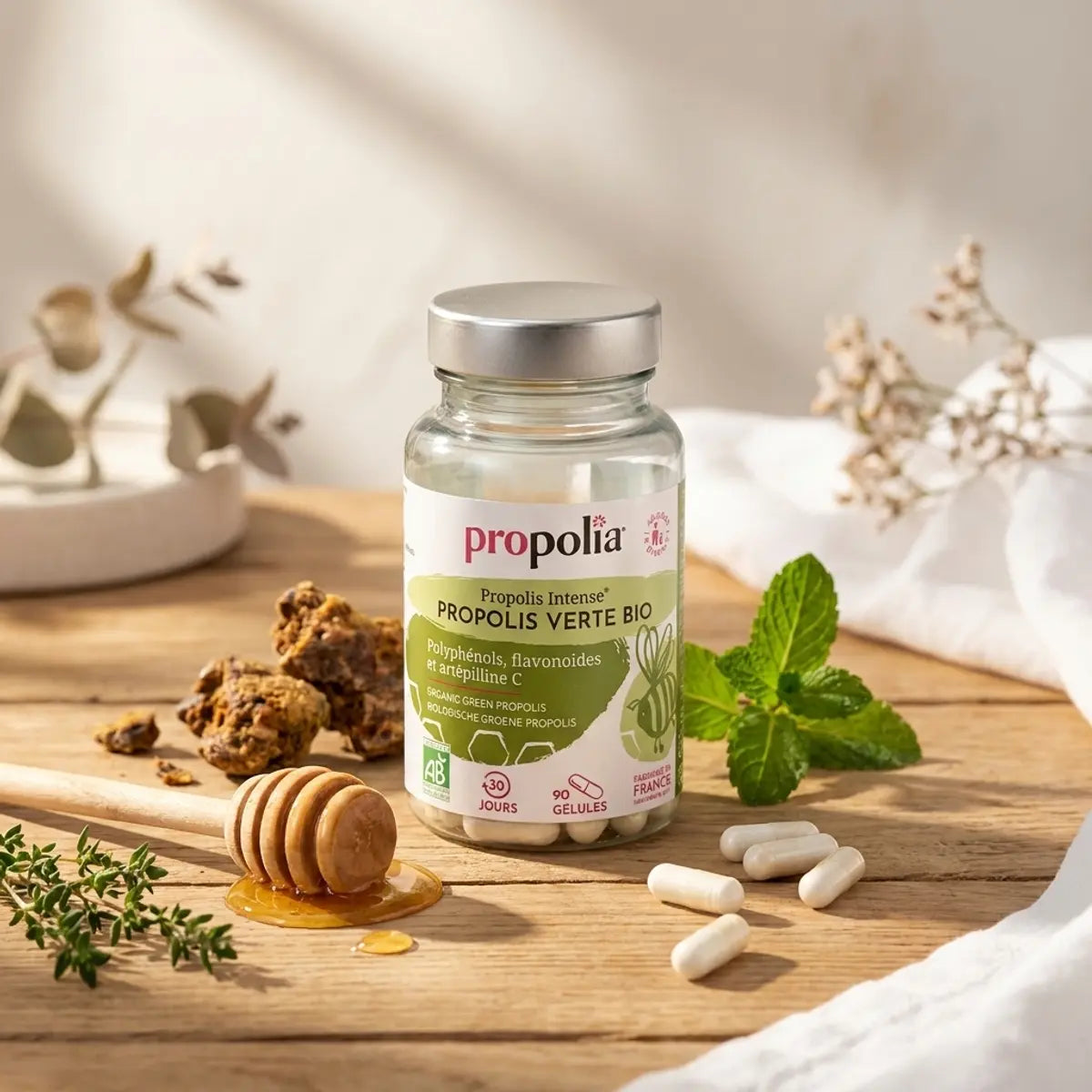 Gélules de propolis verte bio Propolia sur table en bois avec miel et herbes naturelles