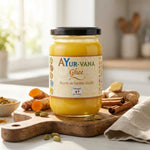Pot de Ghee bio Ayurvana 150g sur surface en bois avec ingrédients naturels et herbes fraîches