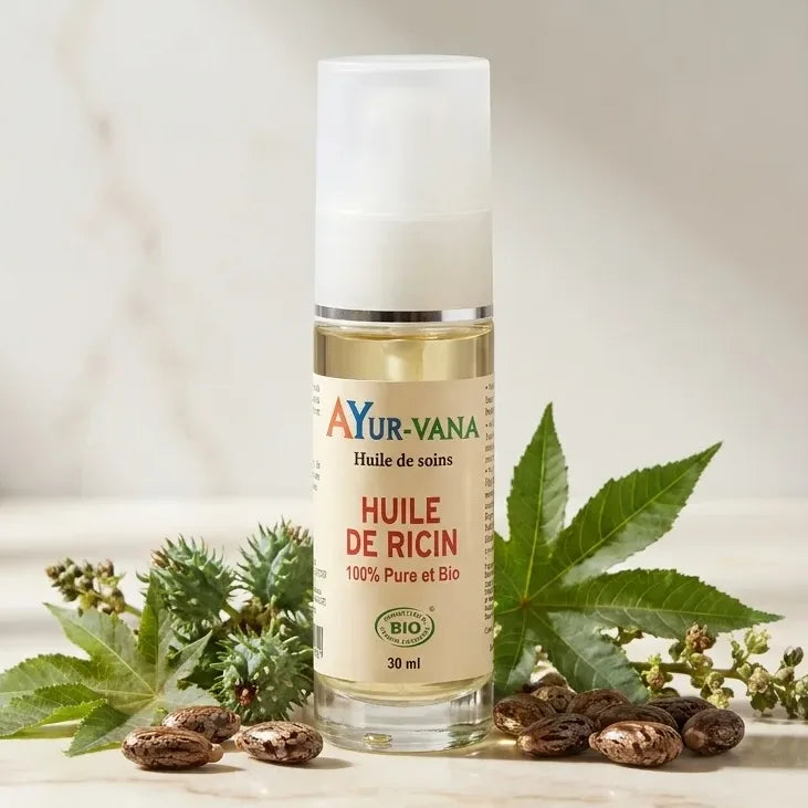Bouteille d'huile de ricin bio Ayurvana avec graines et feuilles sur marbre blanc