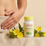 Bouteille huile d'onagre bio en gélules avec fleurs jaunes et main de femme sur abdomen
