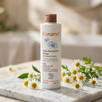 Huile nettoyante visage bio Florame flacon blanc avec capuchon bronze sur fond spa