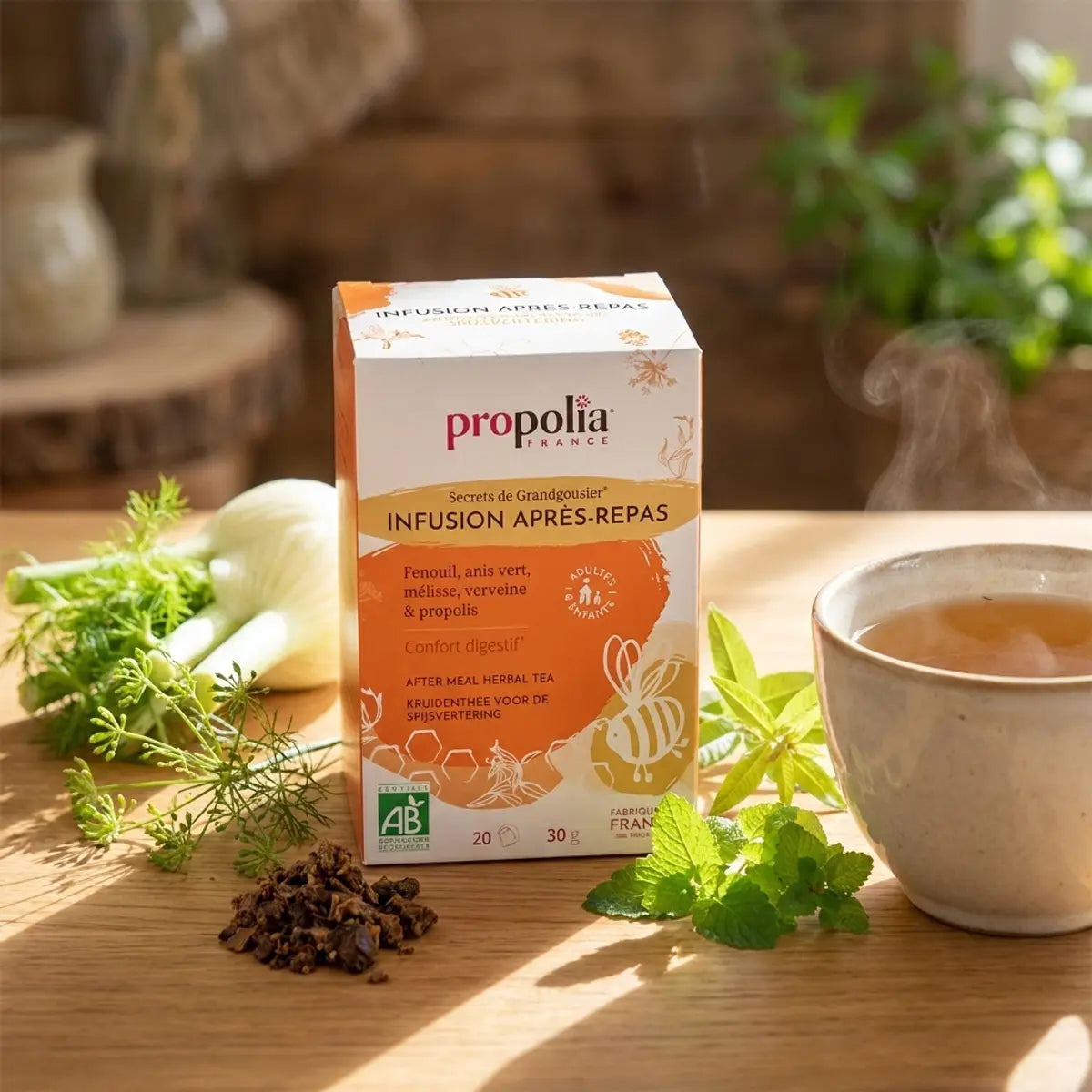 Infusion bio Propolia après-repas en sachets avec herbes fraîches et tasse fumante sur table en bois