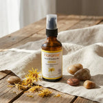 Macérât huileux d'Arnica bio Florame avec fleurs séchées et pierres lisses sur bois