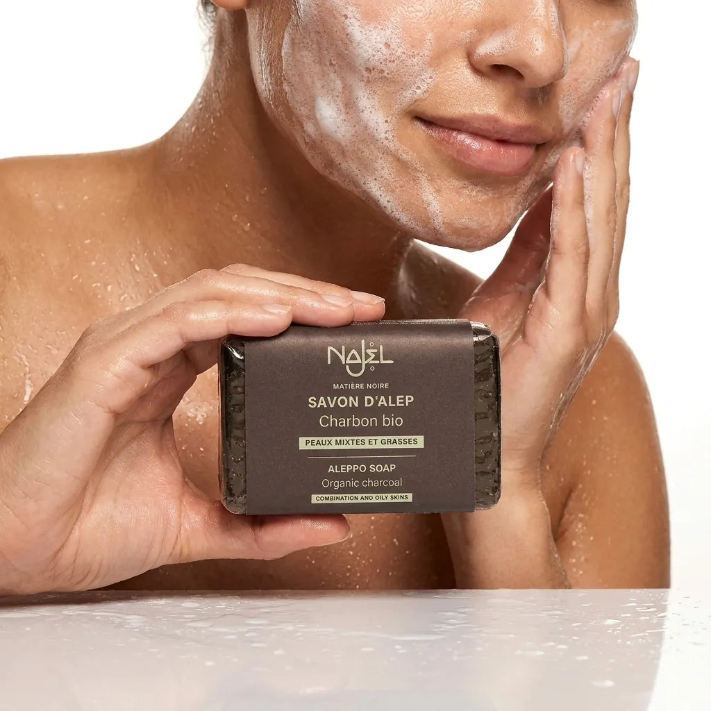 Savon d'Alep au charbon végétal Najel utilisé lors du nettoyage facial avec mousse et gouttes d'eau