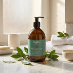 Savon d'Alep liquide Najel bio sur surface en marbre avec feuilles de laurier et accessoires minimalistes
