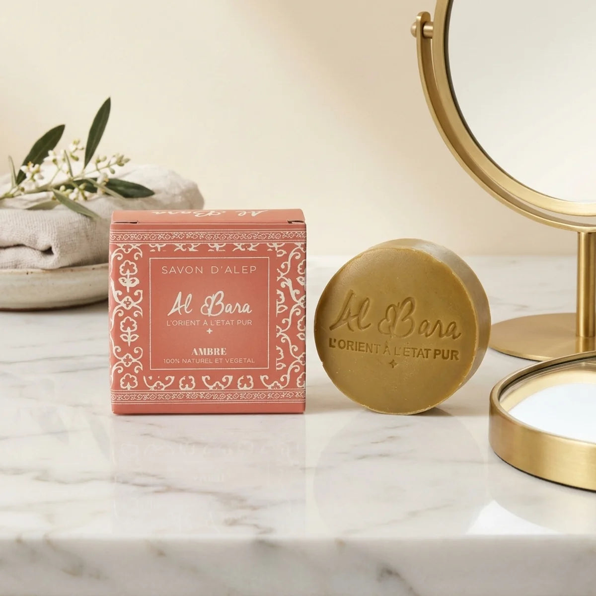 Savon d'Alep parfumé Ambre Al Bara 50g sur vanité marbre, packaging terracotta et savon doré