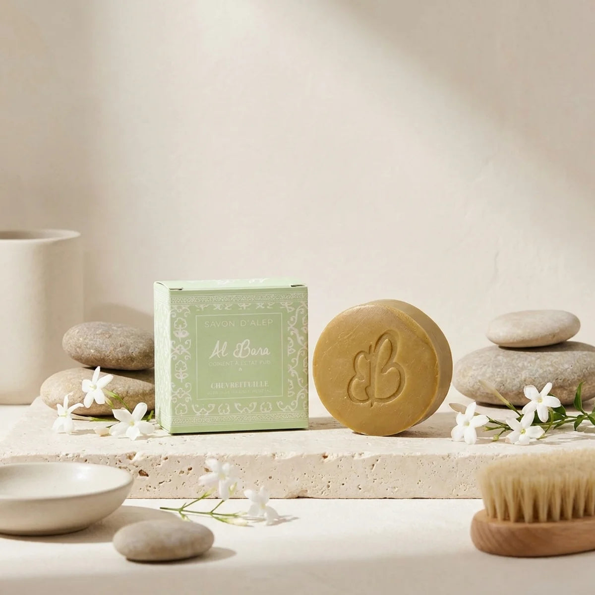 Savon d'Alep Chèvrefeuille Al Bara avec emballage vert et bar doré dans un décor spa luxe