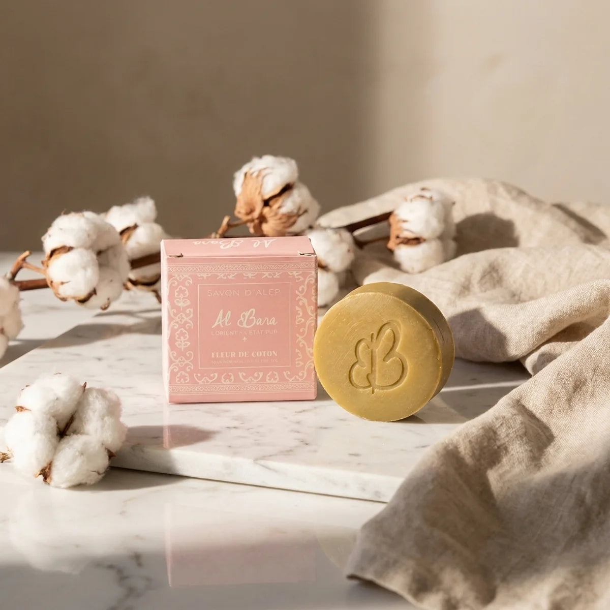 Savon d'Alep Al Bara parfum fleur de coton sur marbre avec emballage rose et fleurs de coton
