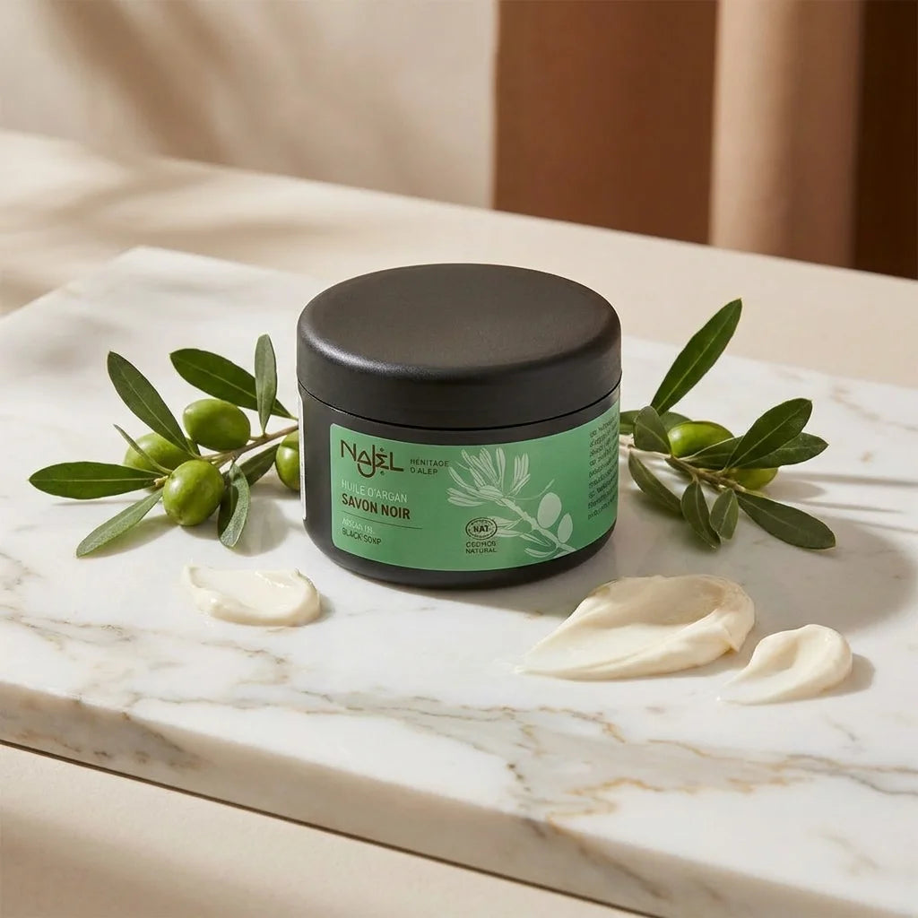 Savon noir Najel à l'huile d'argan en pot sur marbre avec branches d'argan