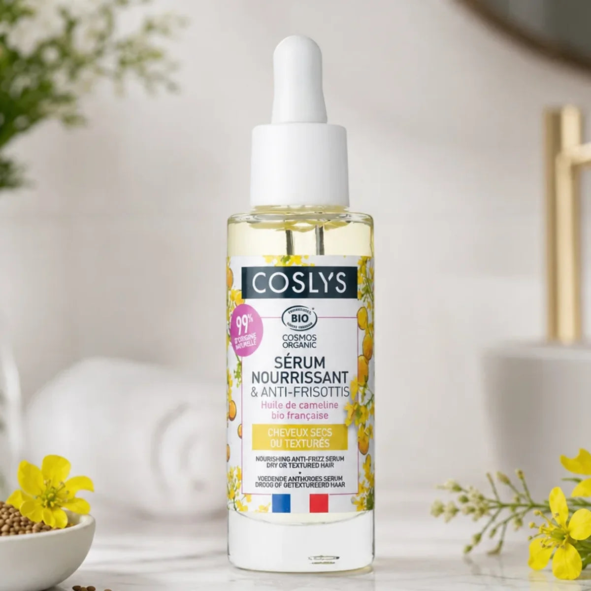Sérum nourrissant bio Coslys 30ml avec pipette, fleurs de caméline et ingrédients naturels sur marbre blanc