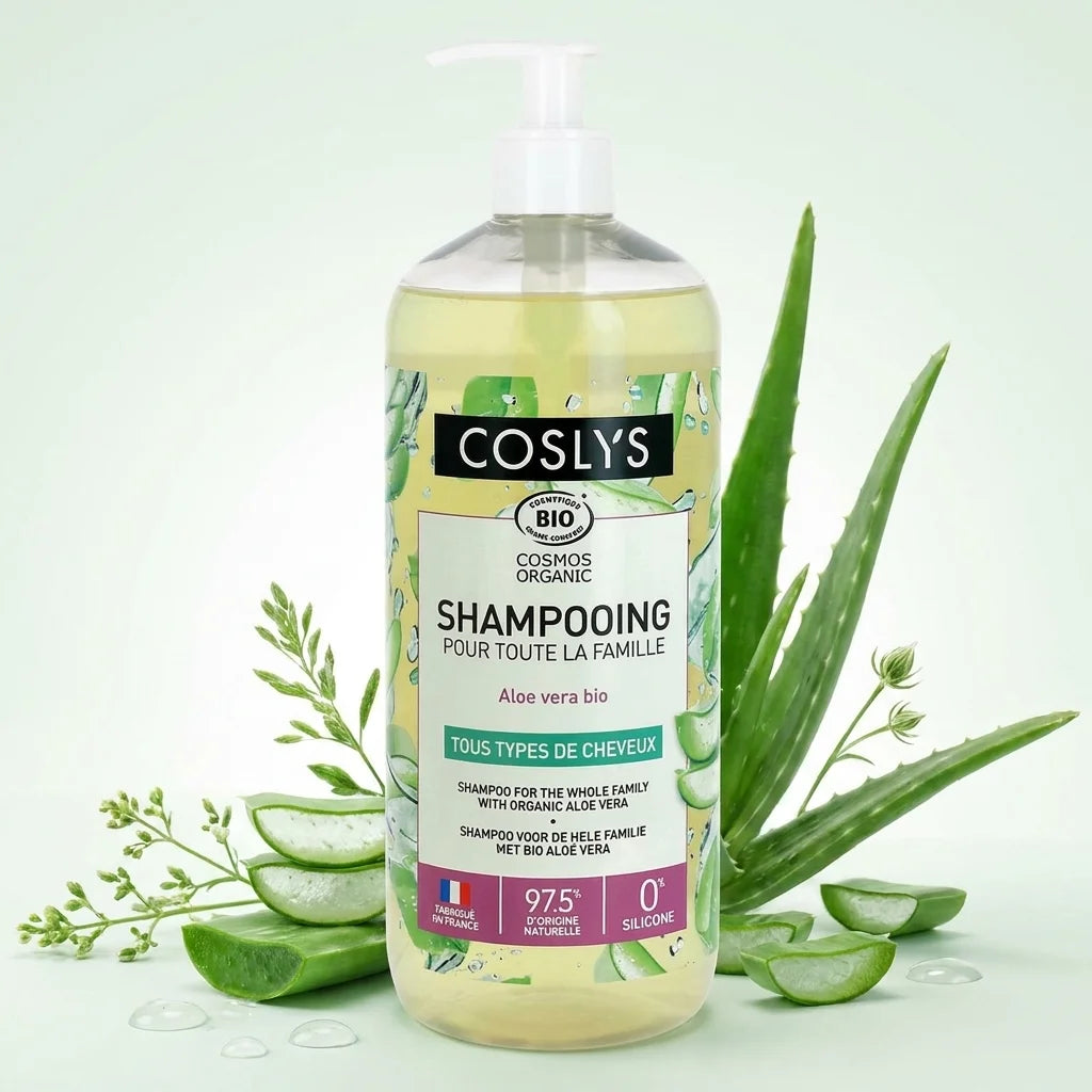 Shampooing Aloe vera bio Coslys avec feuilles fraîches et gouttes d'eau sur fond blanc