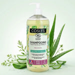 Shampooing Aloe vera bio Coslys avec feuilles fraîches et gouttes d'eau sur fond blanc