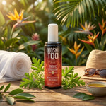 Spray anti-moustiques Moskitoo Tropic Citriodora entouré de plantes citronelle en jardin tropical