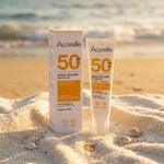 Spray solaire SPF 50 bio Acorelle sur serviette de plage avec coquillages et océan
