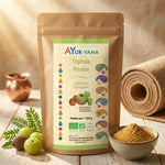 Triphala bio Ayurvana en poudre sur surface bois avec herbes et bol dans ambiance wellness ayurvédique