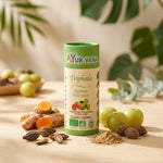Gélules Triphala bio vegan Ayurvana avec curcuma, amla et herbes sur fond bois naturel