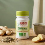 Flacon Triphala Bio vegan en gélules entouré d'herbes et tasse de thé wellness