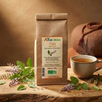 Tulsi bio Ayurvana 100g avec feuilles fraîches et fleurs violettes sur surface bois
