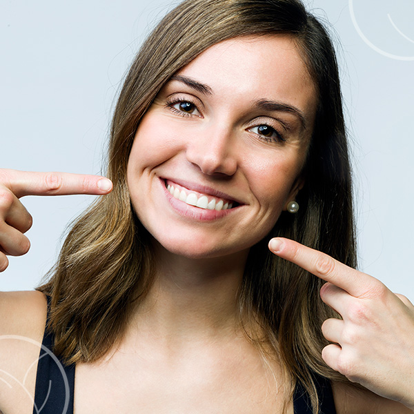 Photo d'une jeune femme souriant et montrant ses dents avec ses doigts