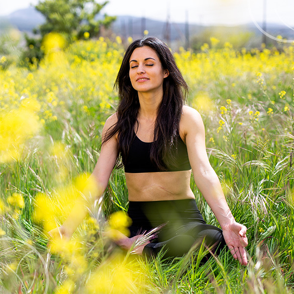 Photo d'une femme faisant du yoga dans un champ de fleurs jaunes