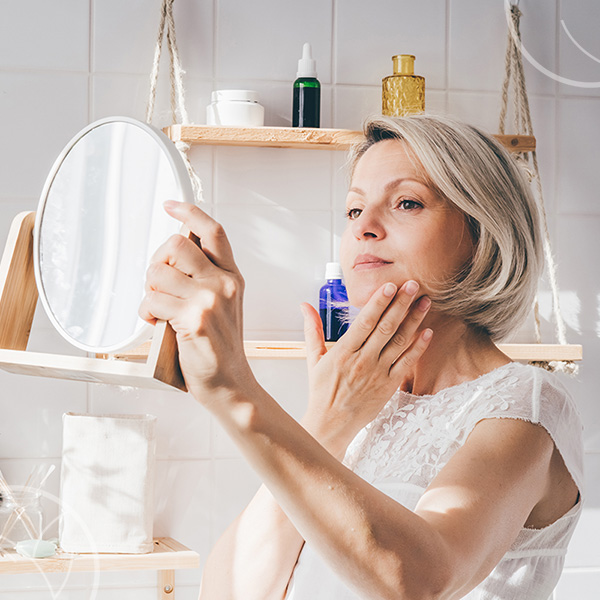 Photo d'une femme qui se regarde dans un miroir de poche