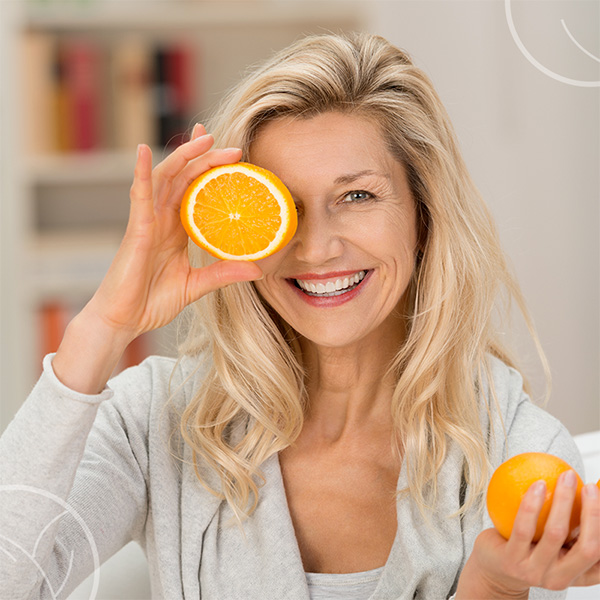 Photo d'une femme tenant des oranges dont une découpée